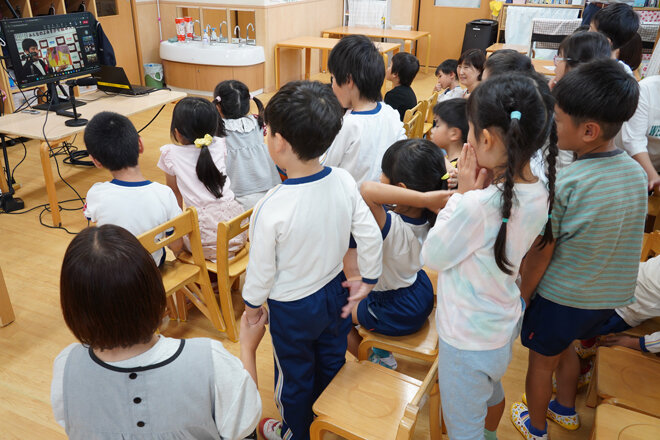 2025年10月にオンラインで開催した第1回の授賞式(左奥の画面)を見守る、埼玉県の絵本寄贈先保育園の園児さんと保育士さん